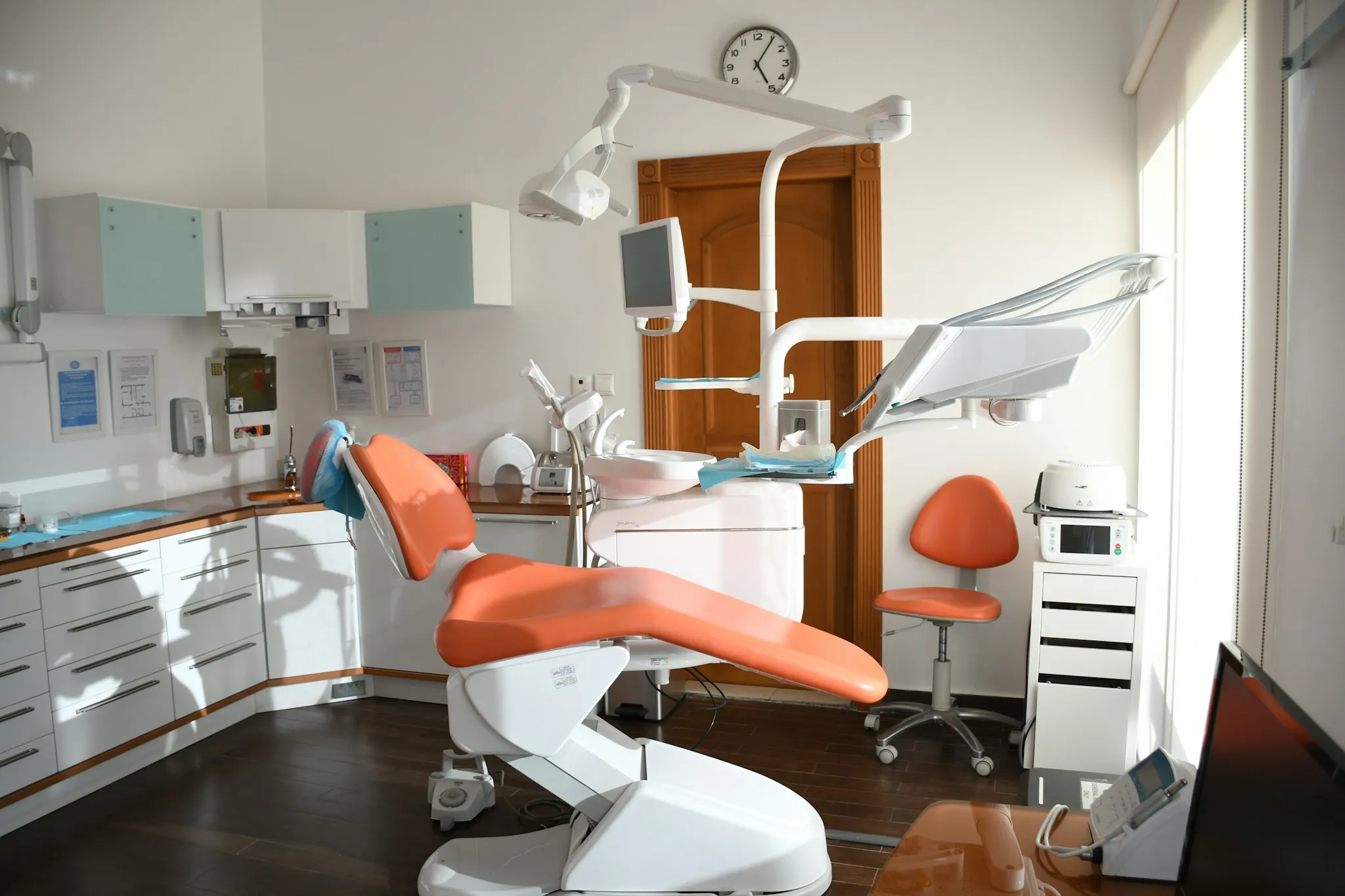 A bright dental clinic with an orange treatment chair