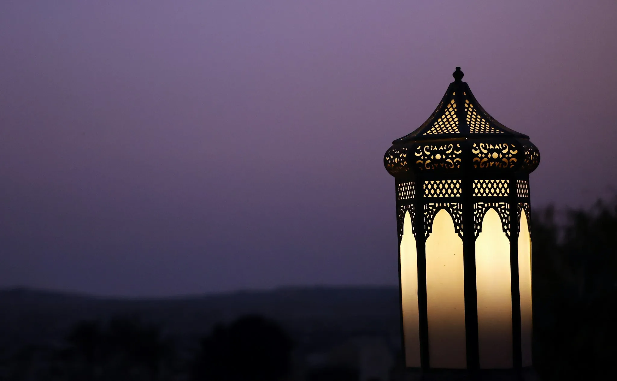 An ornate lantern glowing against a twilight sky