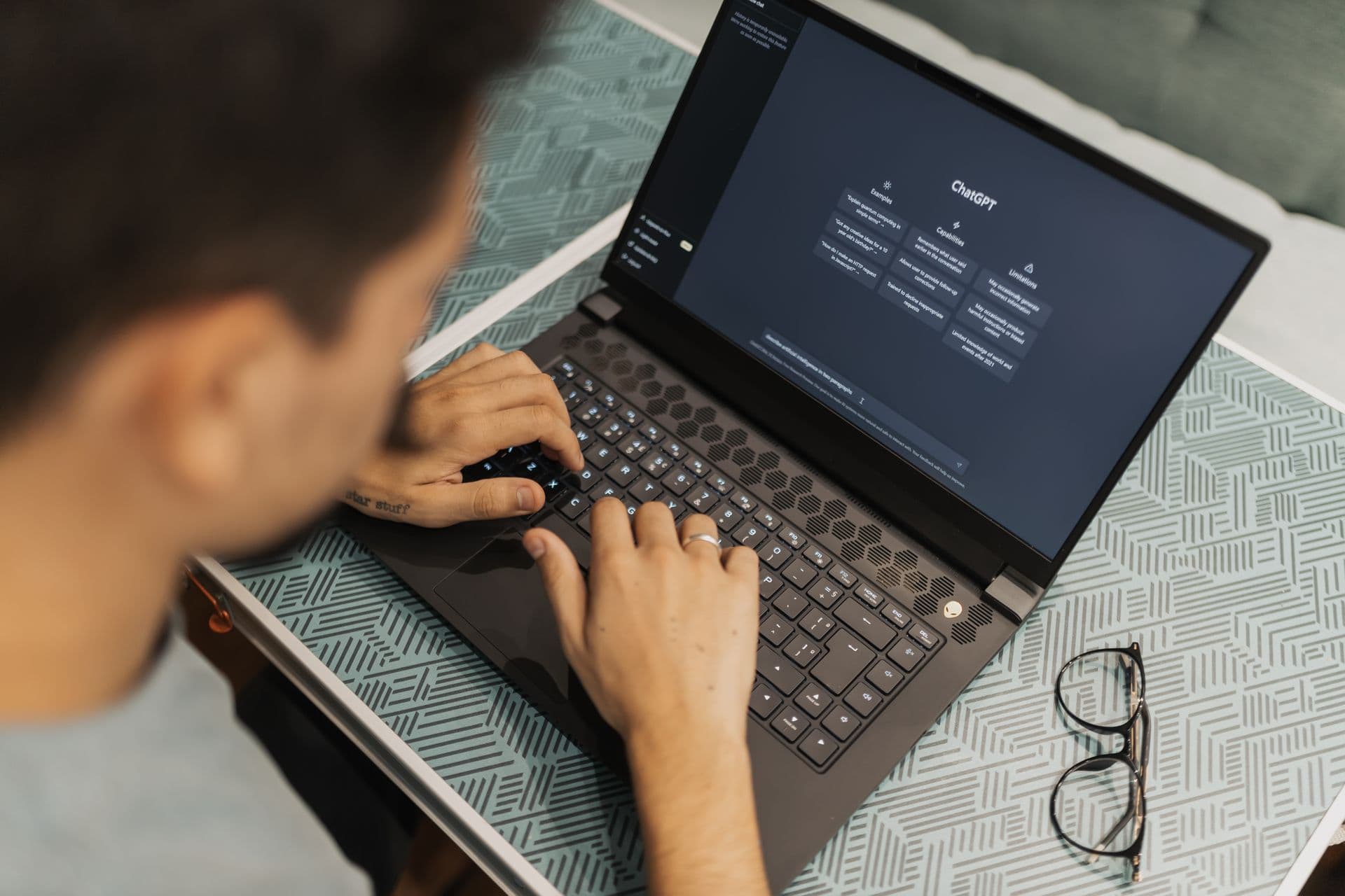 Man typing on a laptop with an AI chatbot open on the screen