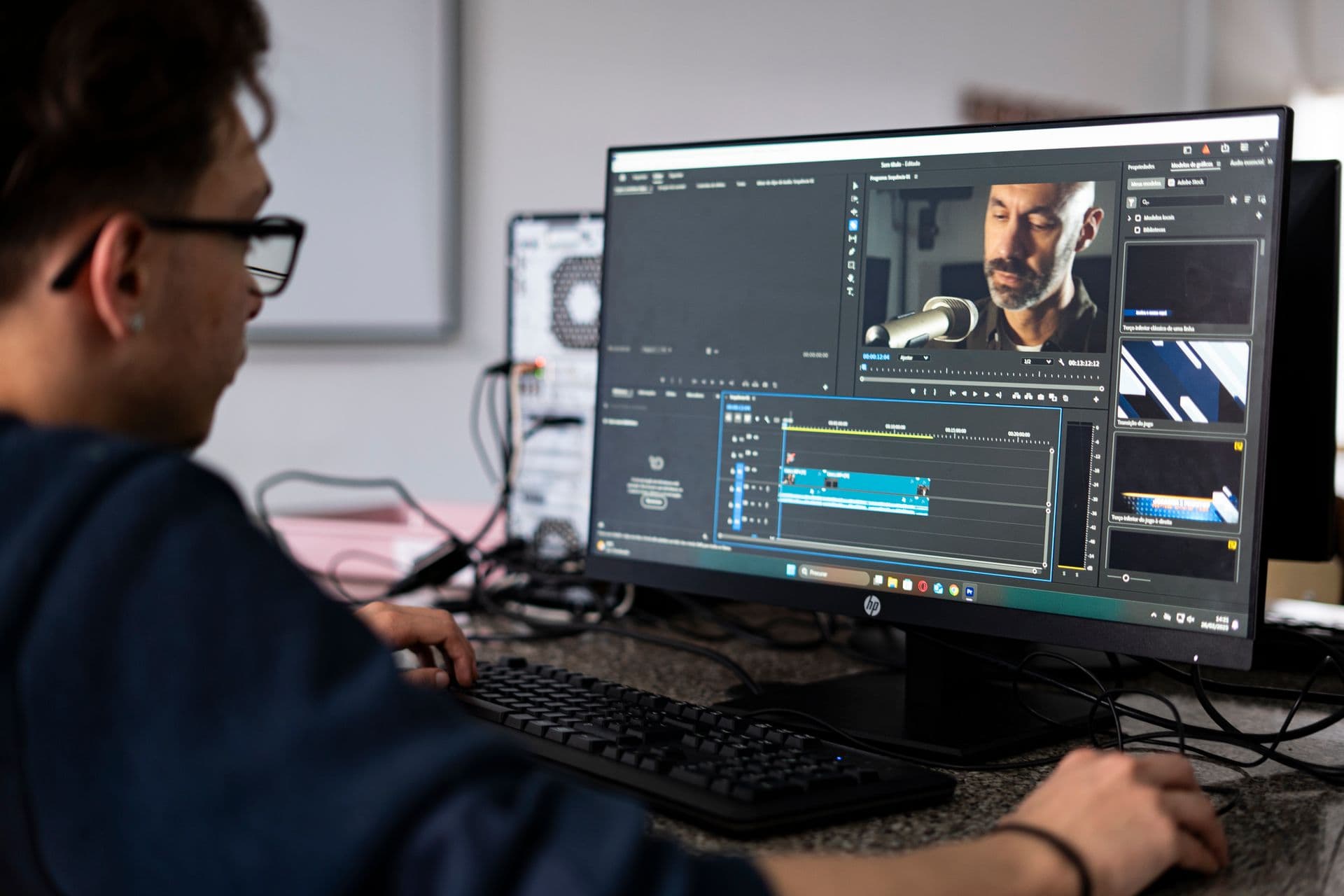 Video editor working on an editing timeline on a desktop monitor in an office