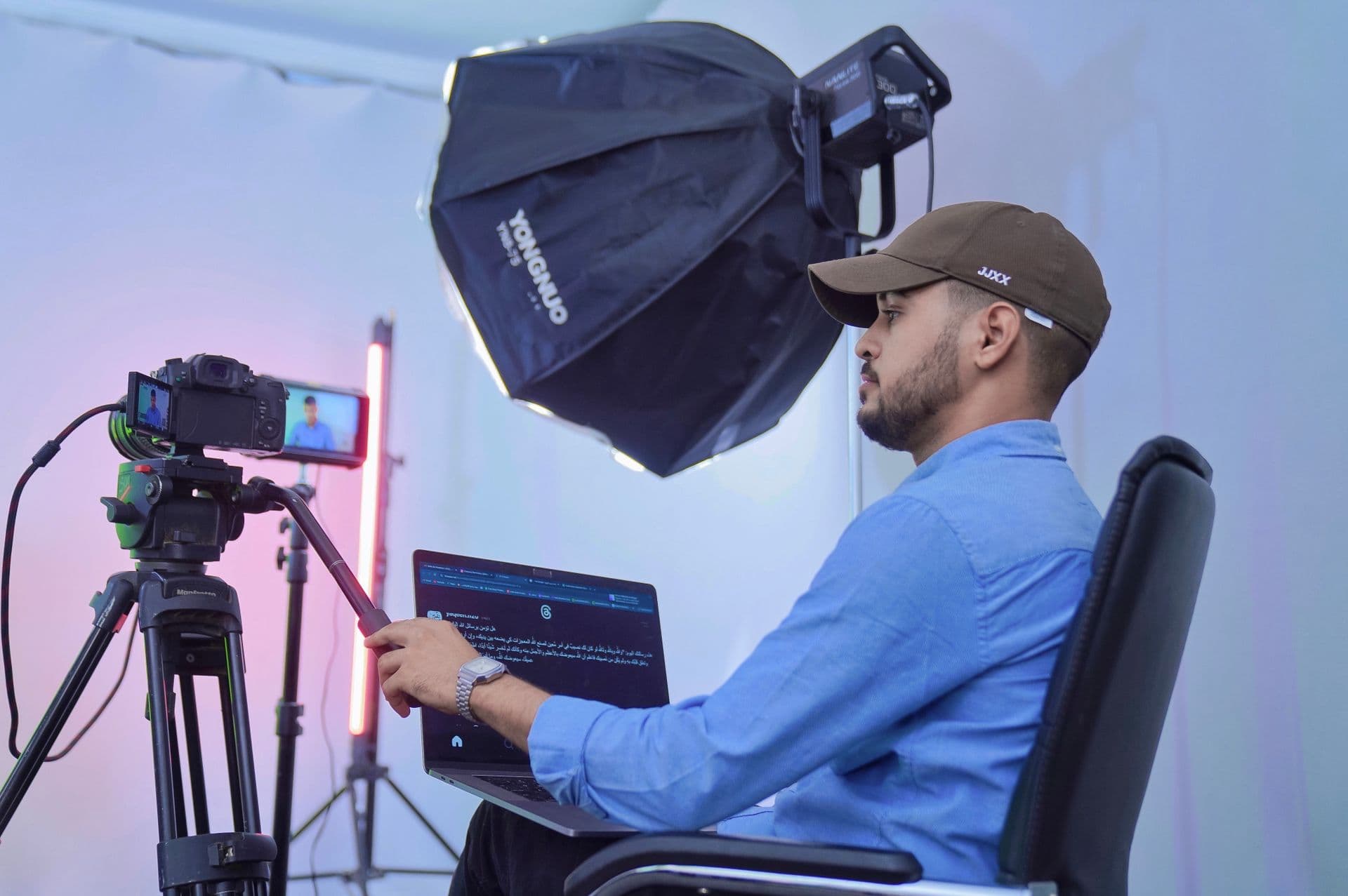 Creator operating a camera on a tripod from a laptop in a studio with softbox lighting