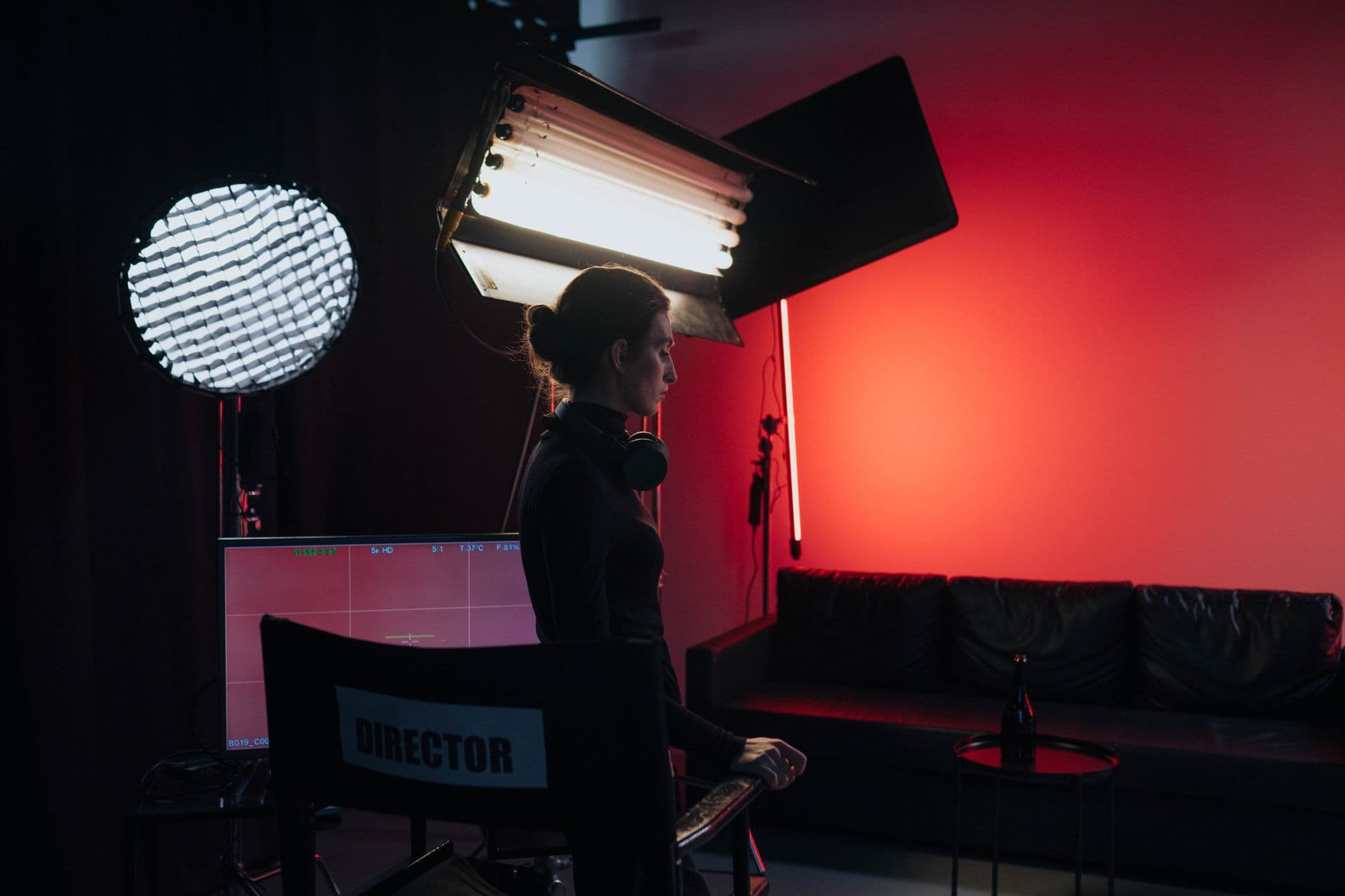 Woman standing beside a director's chair in a studio lit by softbox and strip lights