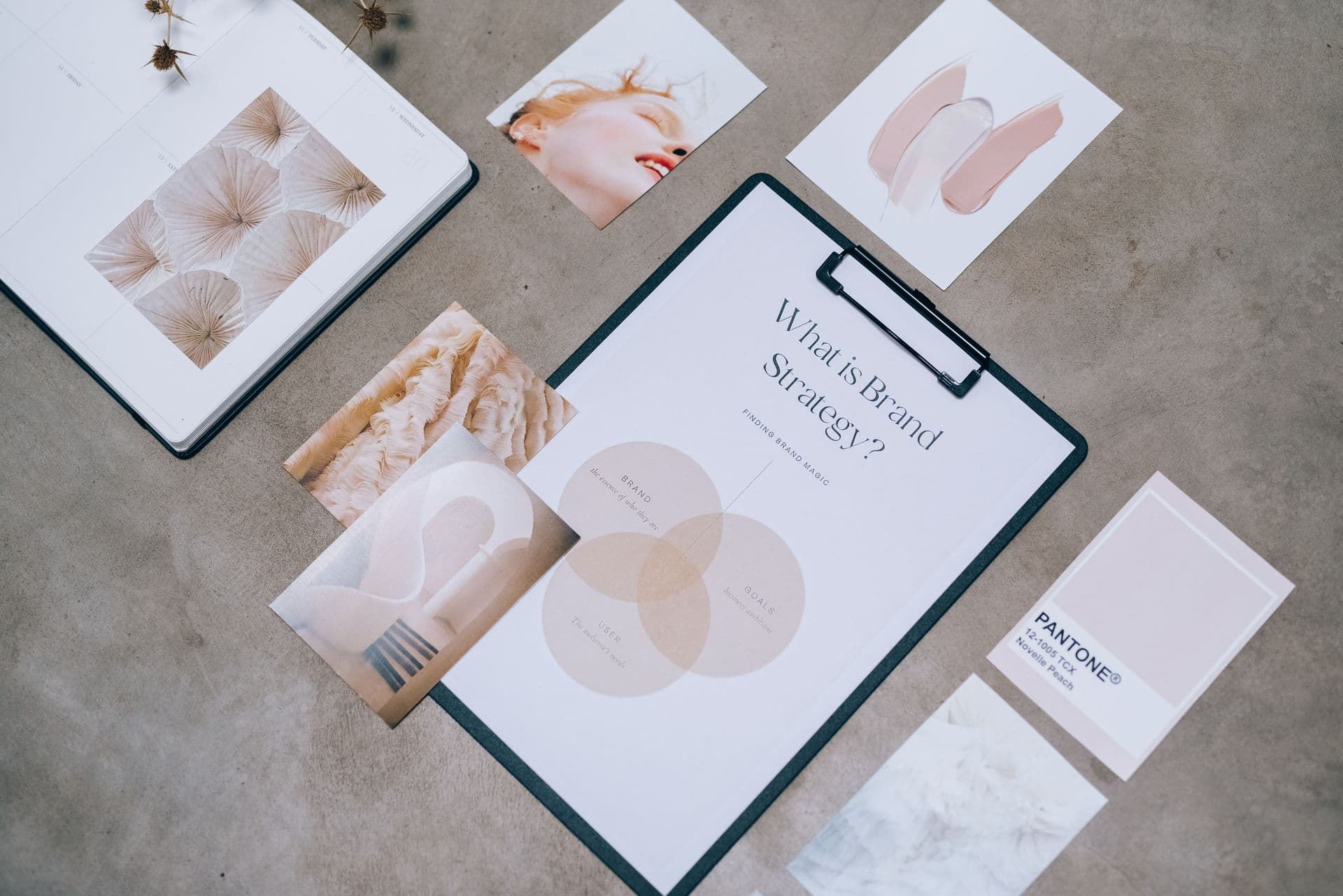 Flat lay of a brand strategy clipboard, mood images and a colour swatch on concrete