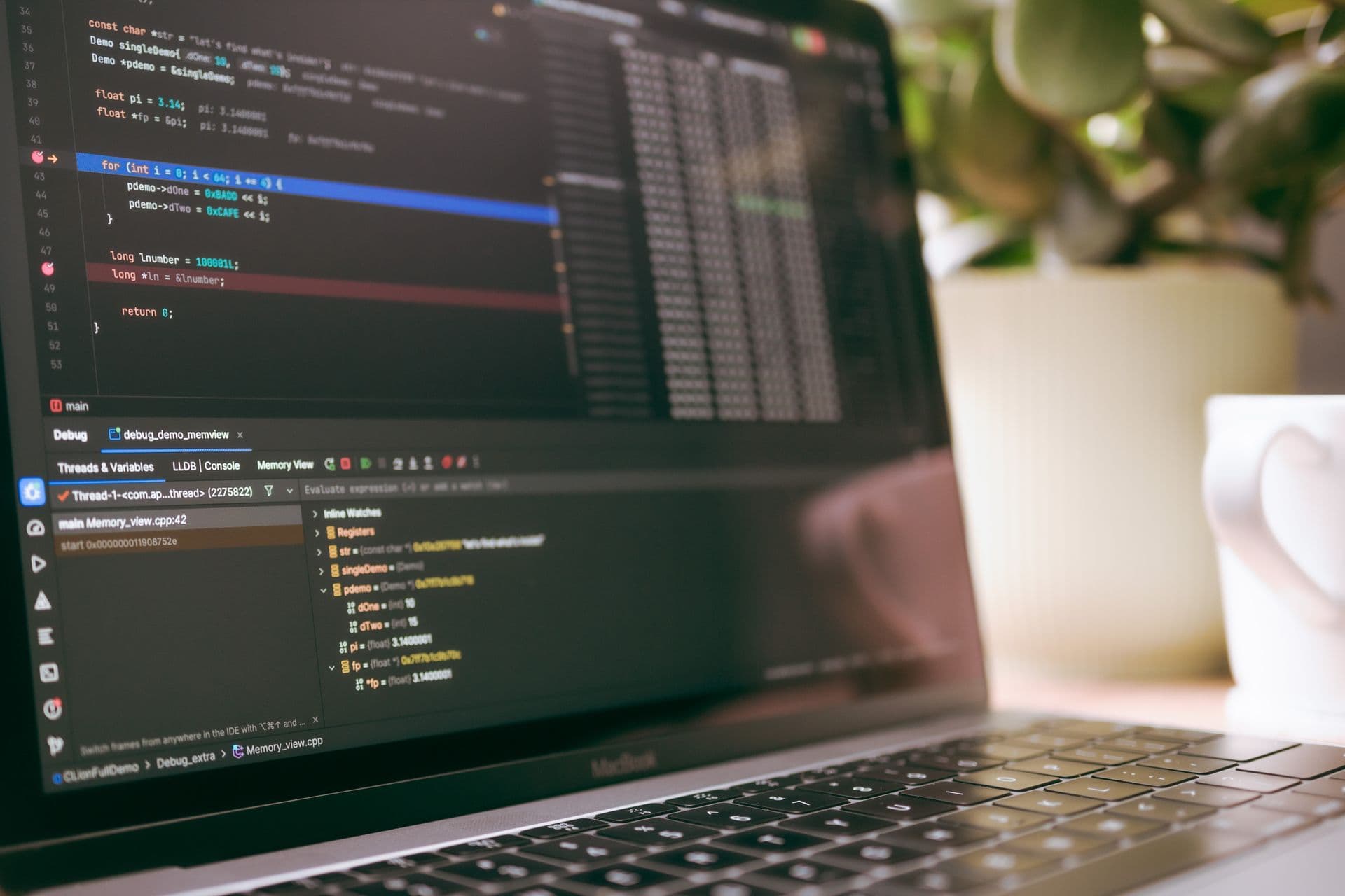 Laptop screen showing source code and a debugger panel in a softly lit workspace