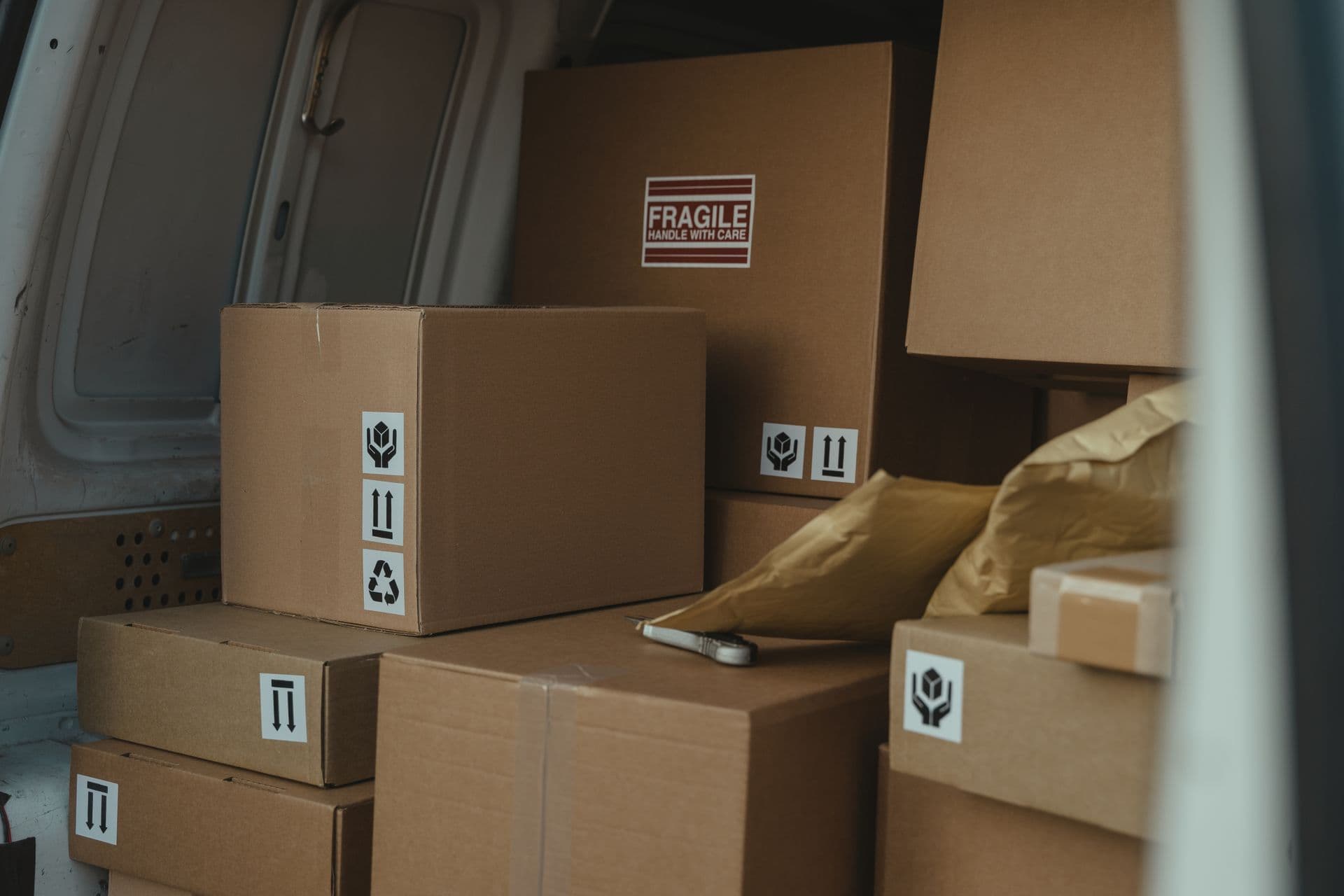 Cardboard parcels with fragile labels stacked inside a delivery van