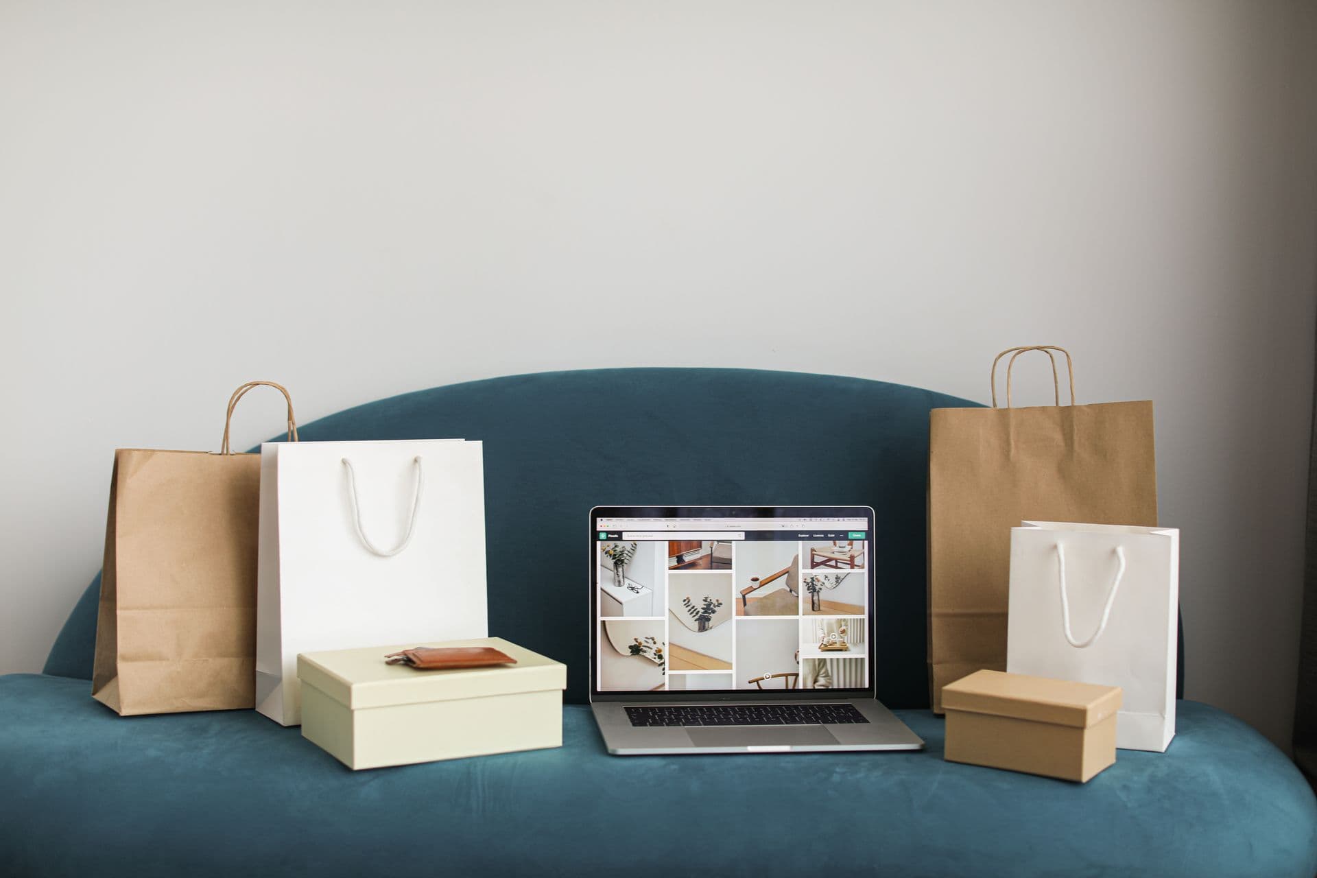 Laptop showing an online store surrounded by shopping bags and gift boxes on a sofa