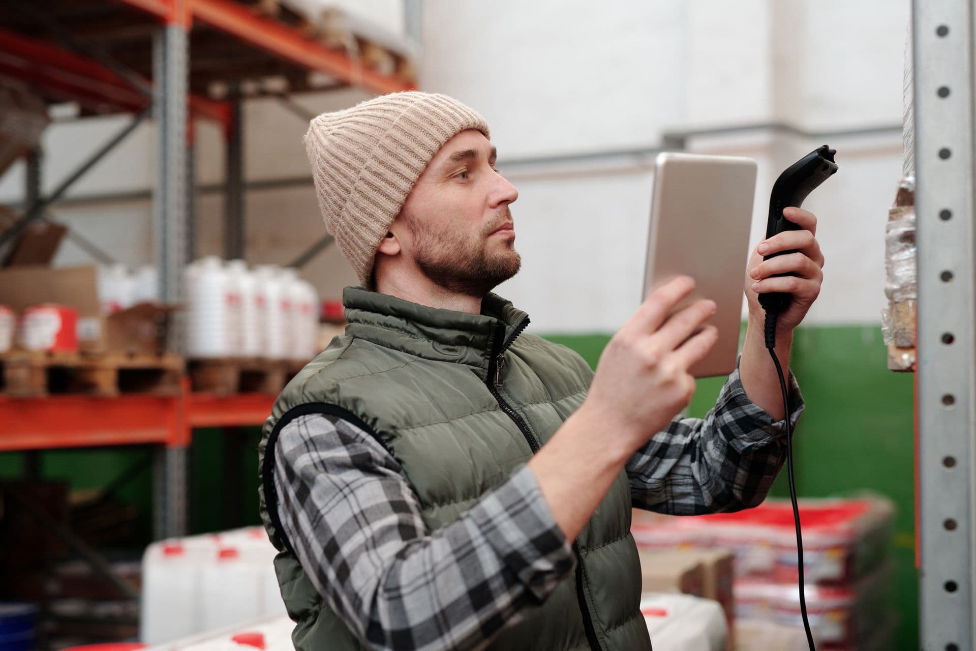 Warehouse worker scanning stock with a handheld scanner and tablet beside shelving
