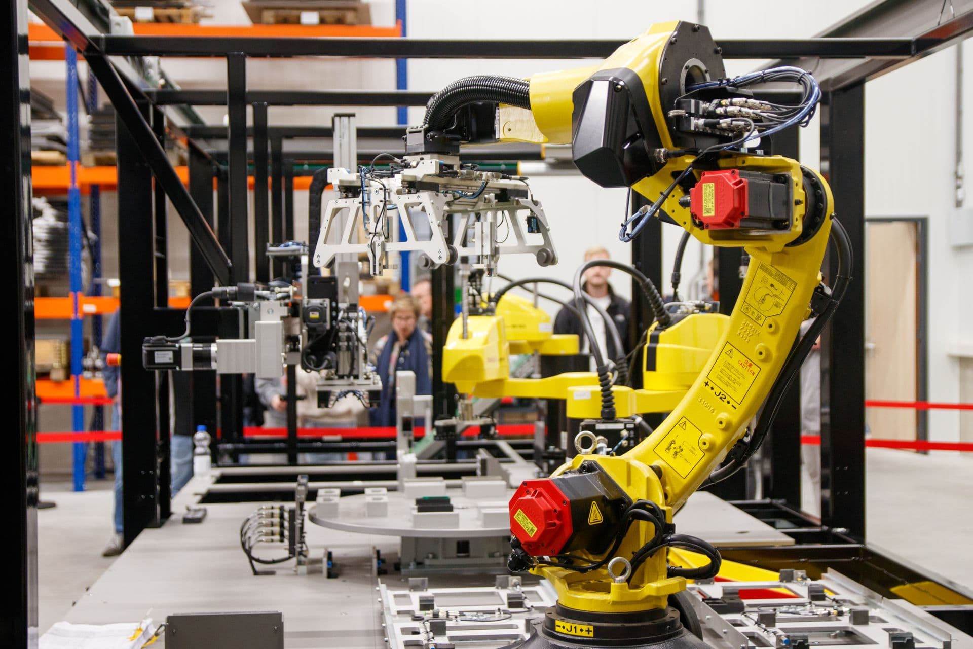 Yellow industrial robot arm working at an automated assembly cell in a factory