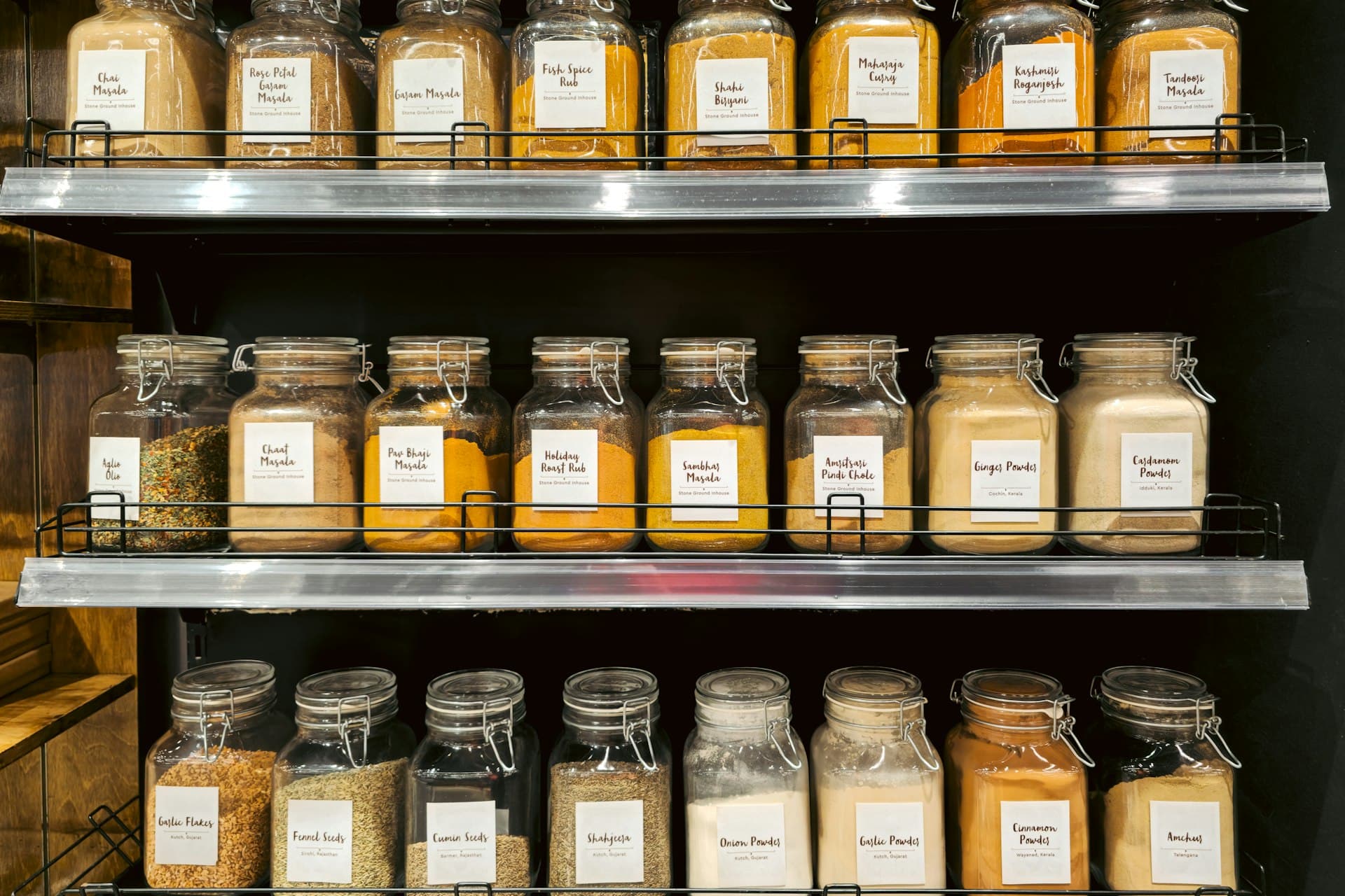 Glass jars of spices, masalas and pulses with paper labels on grocery store shelves in Mumbai