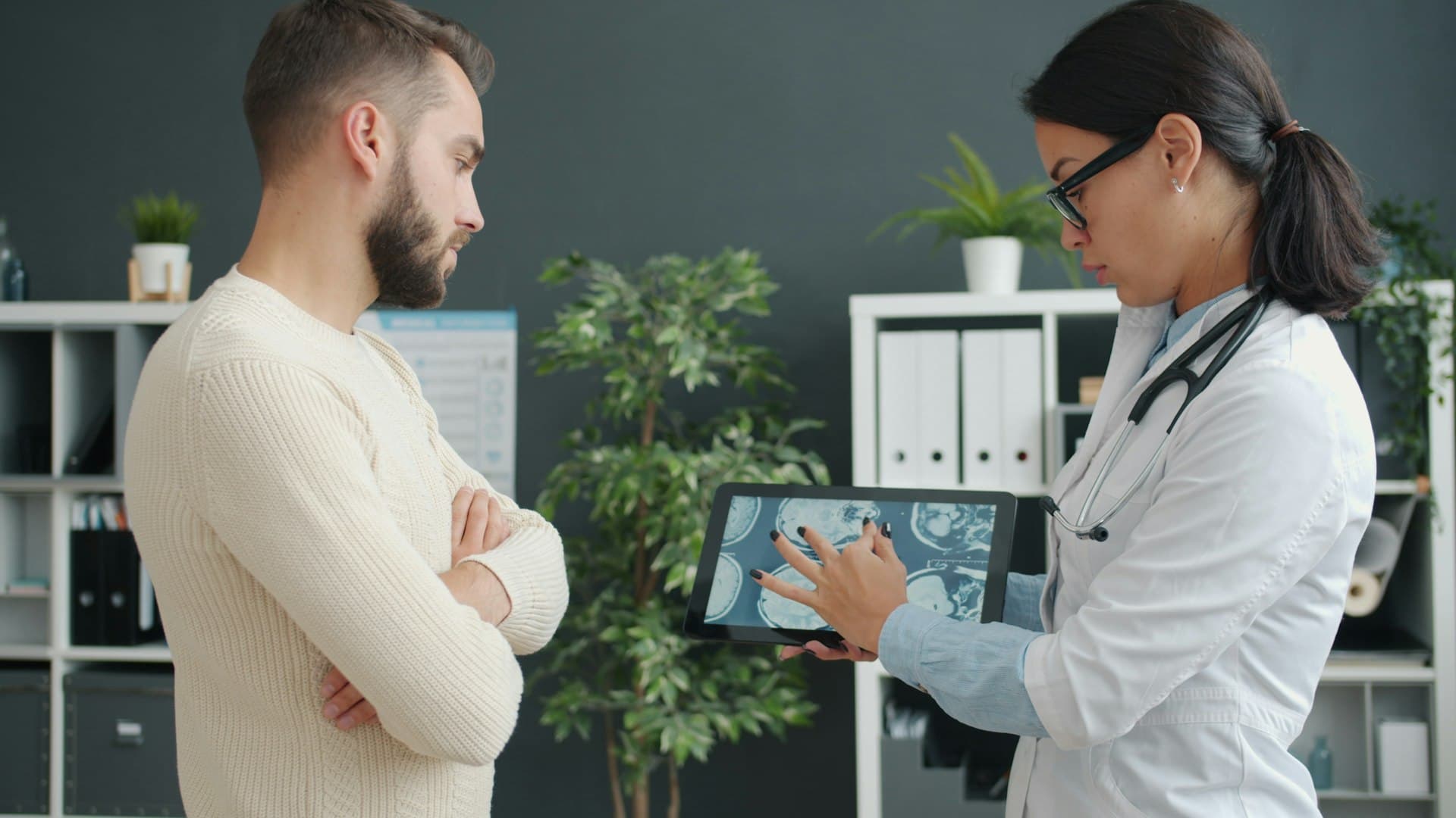 Doctor in a white coat showing a patient a medical scan on a tablet