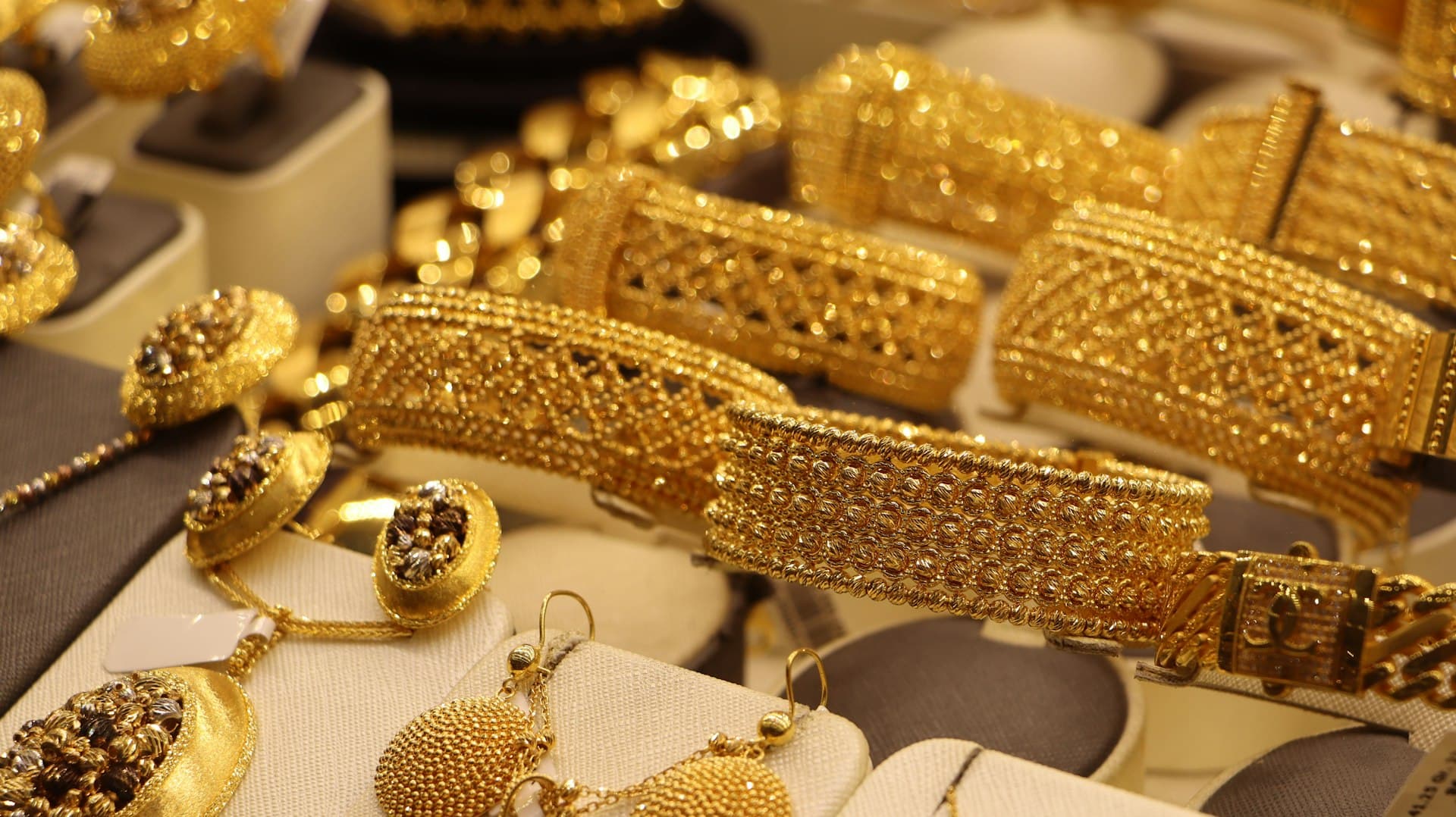 Ornate gold bangles, bracelets and earrings arranged on a jewellery shop display