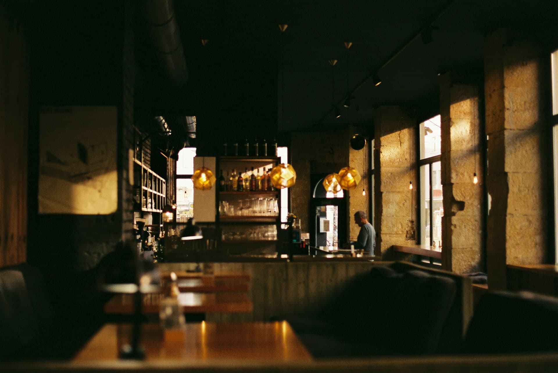 Dimly lit restaurant interior with warm pendant lights, a bar counter and wooden tables