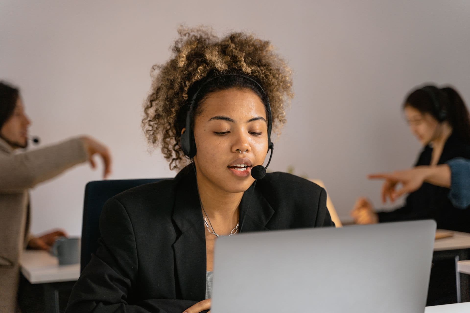 Help desk agent with a headset talking while working on a laptop