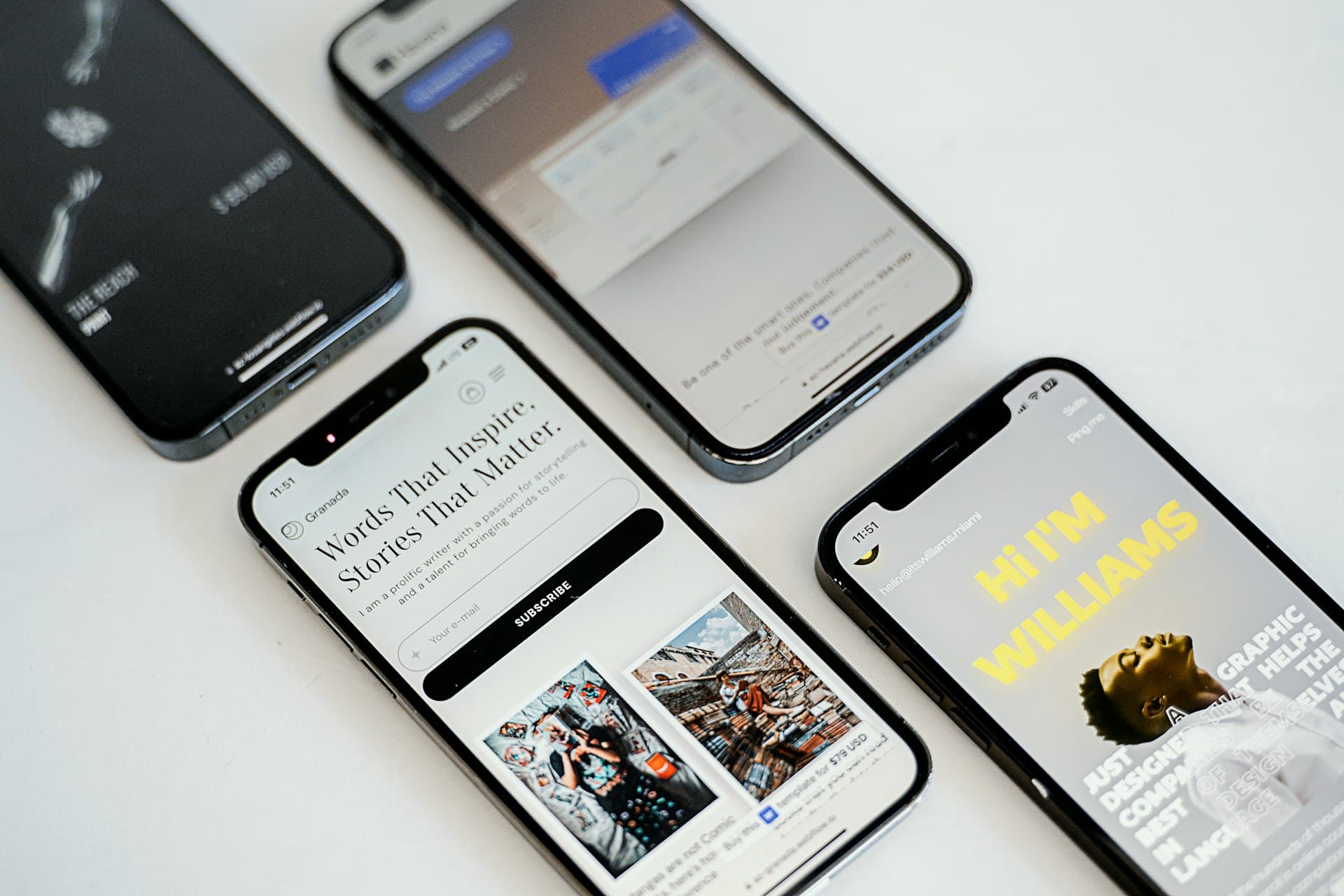Four smartphones on a white table displaying different mobile website and app screens