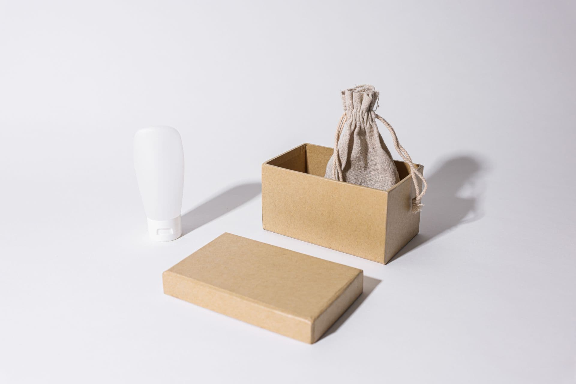 Plain kraft box with a linen pouch and a white cream tube on white