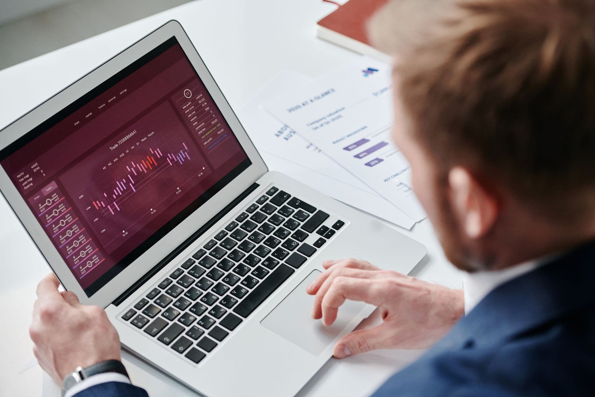Man in a suit reviewing a dark analytics dashboard with charts on a laptop