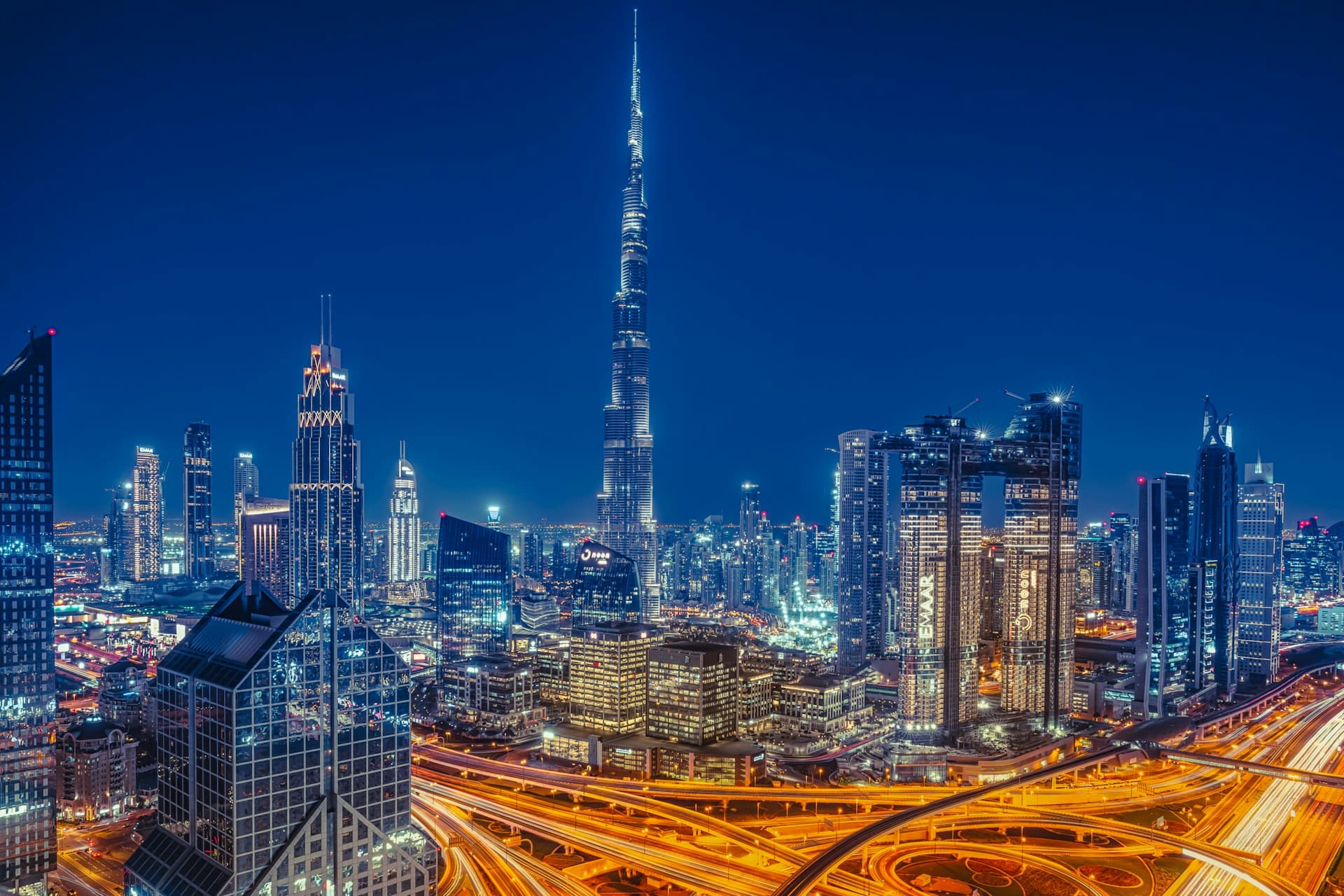 Burj Khalifa rising over the illuminated Downtown Dubai skyline and busy highway interchange at night