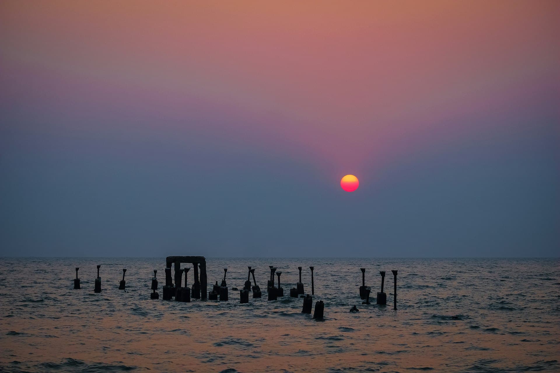 Sunset over the Arabian Sea and the ruined old pier pillars at Kozhikode Beach, Kerala