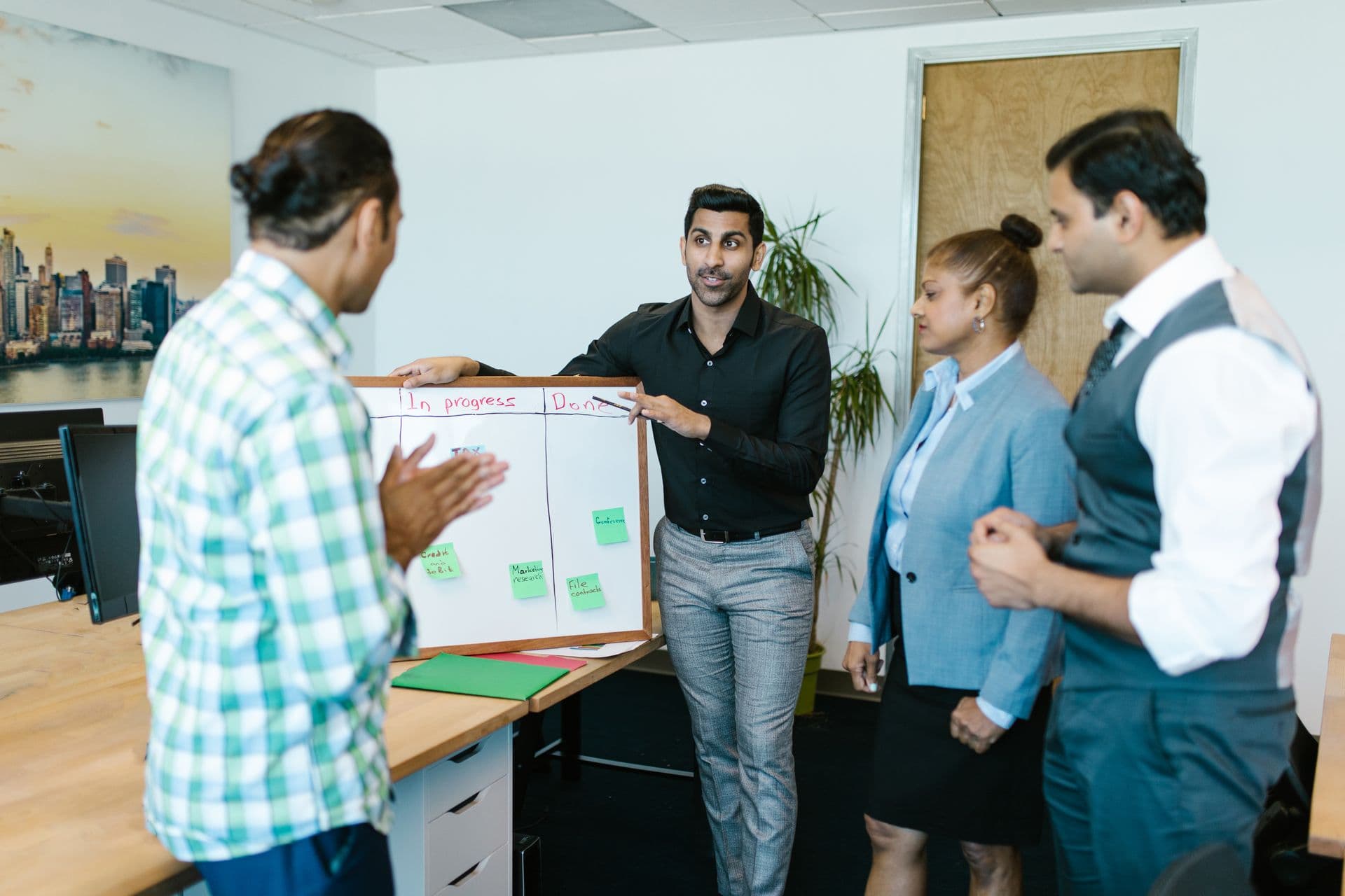 Team standing around an in-progress and done task board during an office meeting