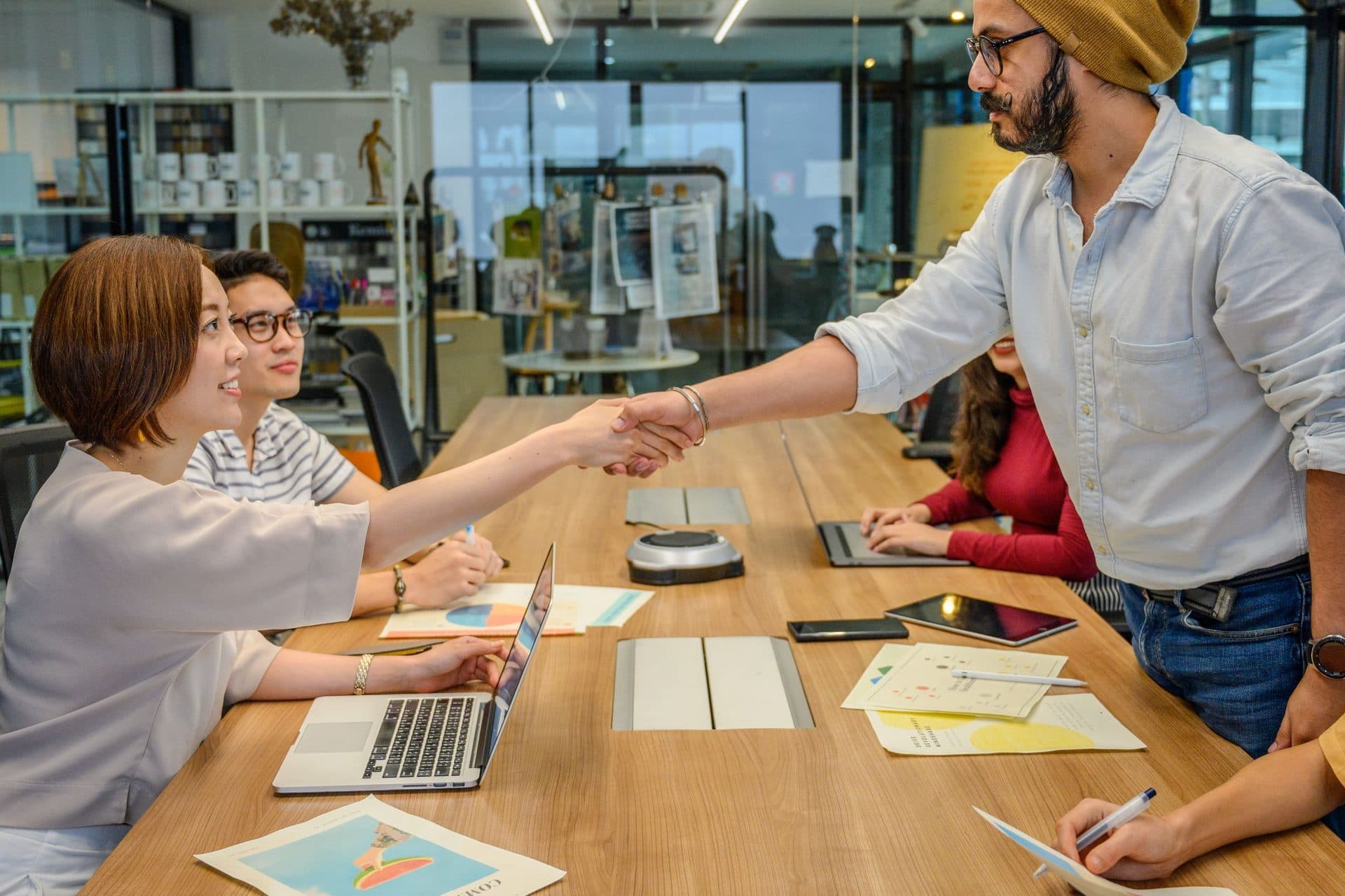 Two colleagues shake hands across a conference table during an office meeting