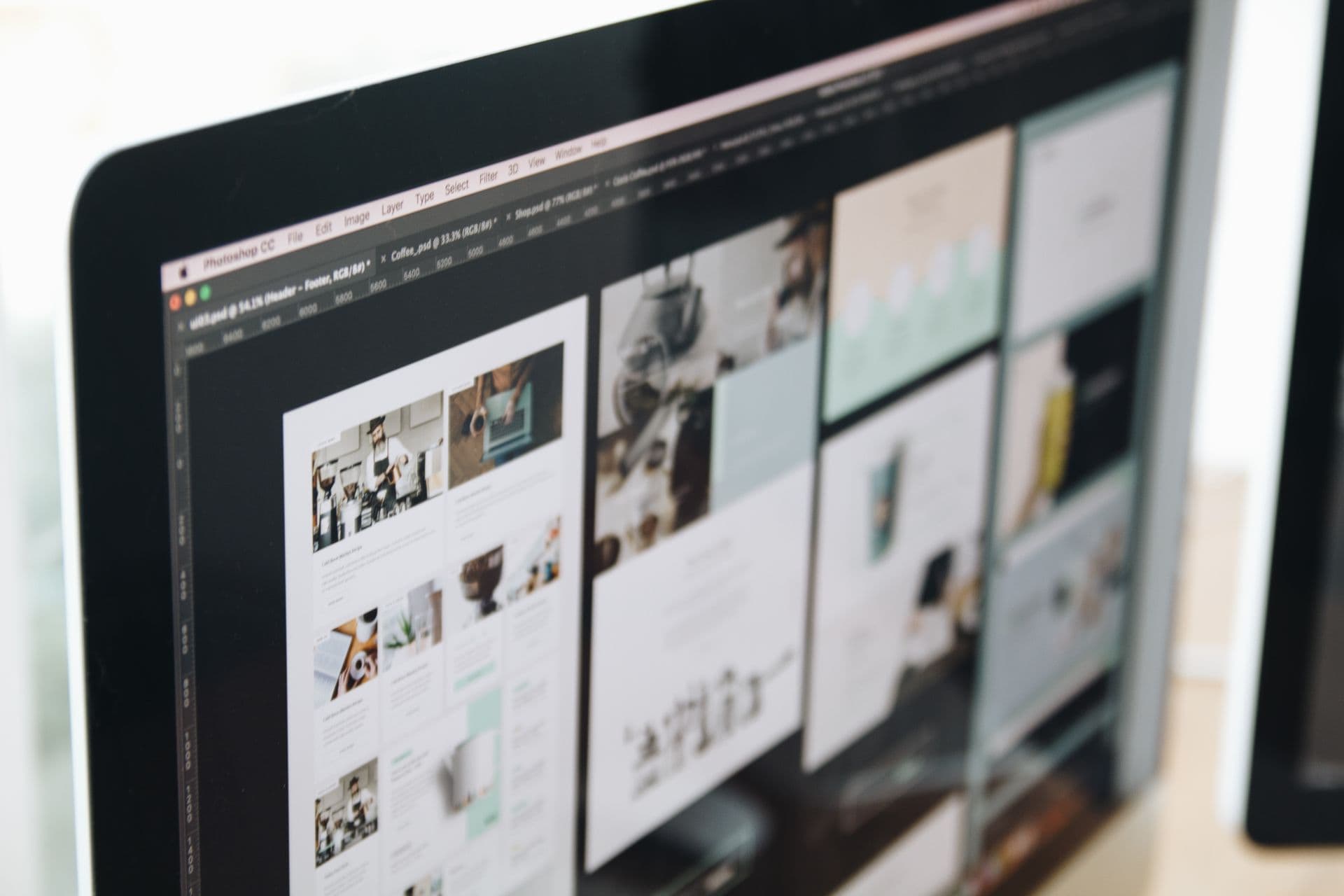 Monitor displaying website layout designs in an image editing program