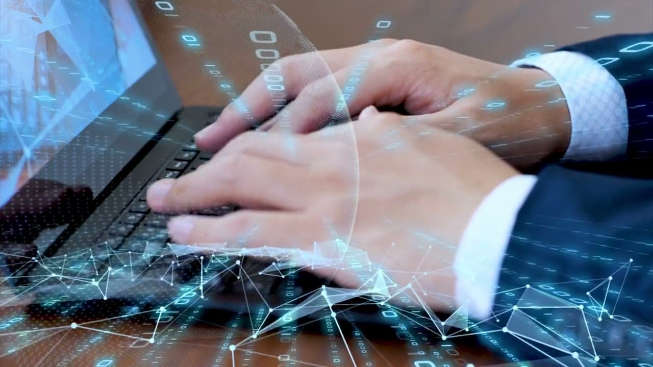 Hands in suit sleeves typing on laptop keyboard with glowing blue network lines overlaid