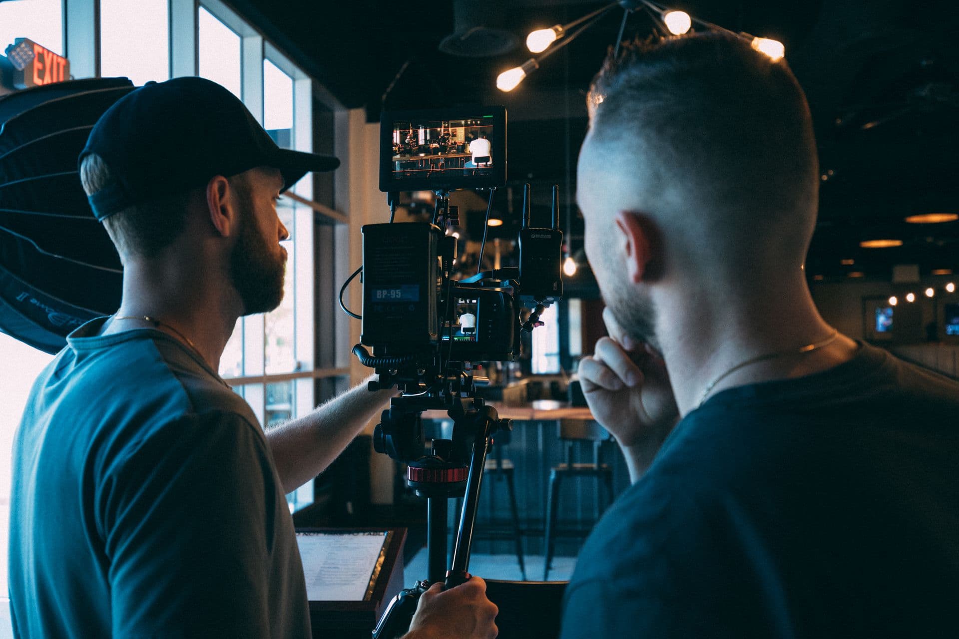Two filmmakers checking the monitor of a camera rig in a dim interior