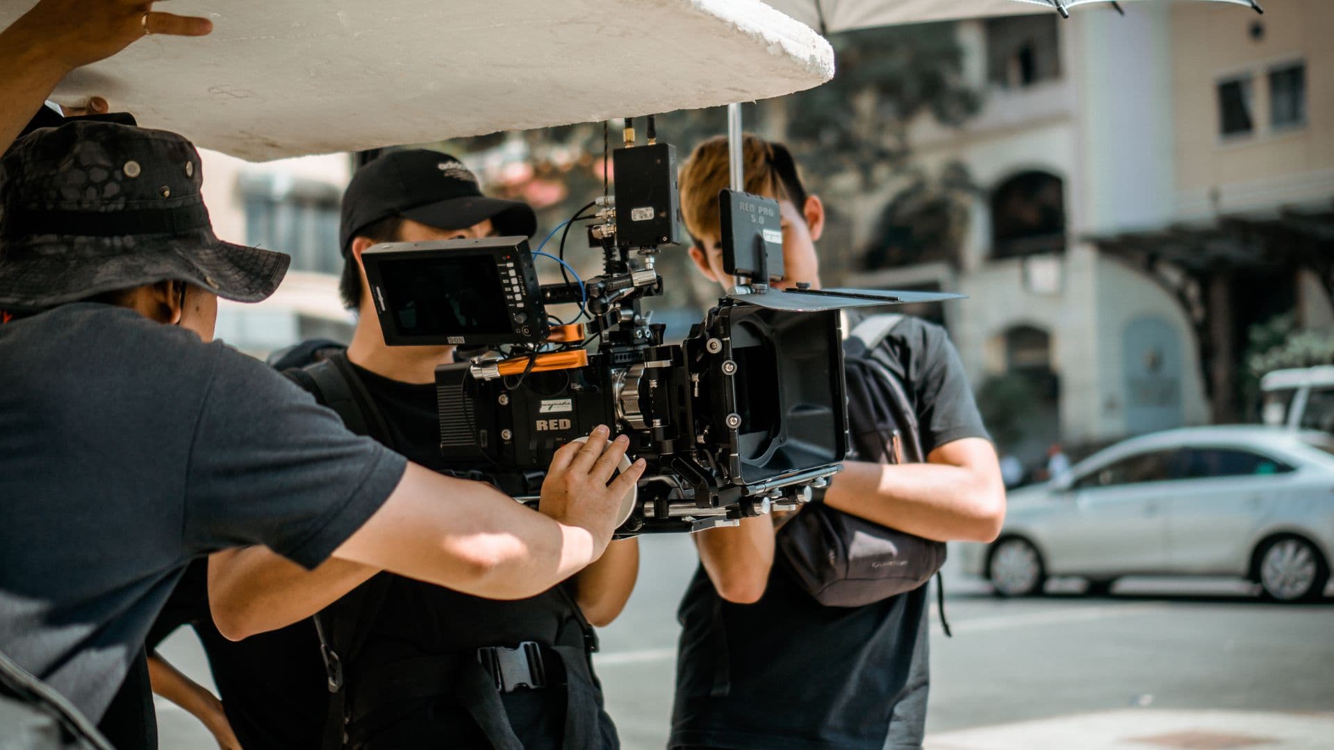 Camera crew operating a cinema camera rig on a sunny city street