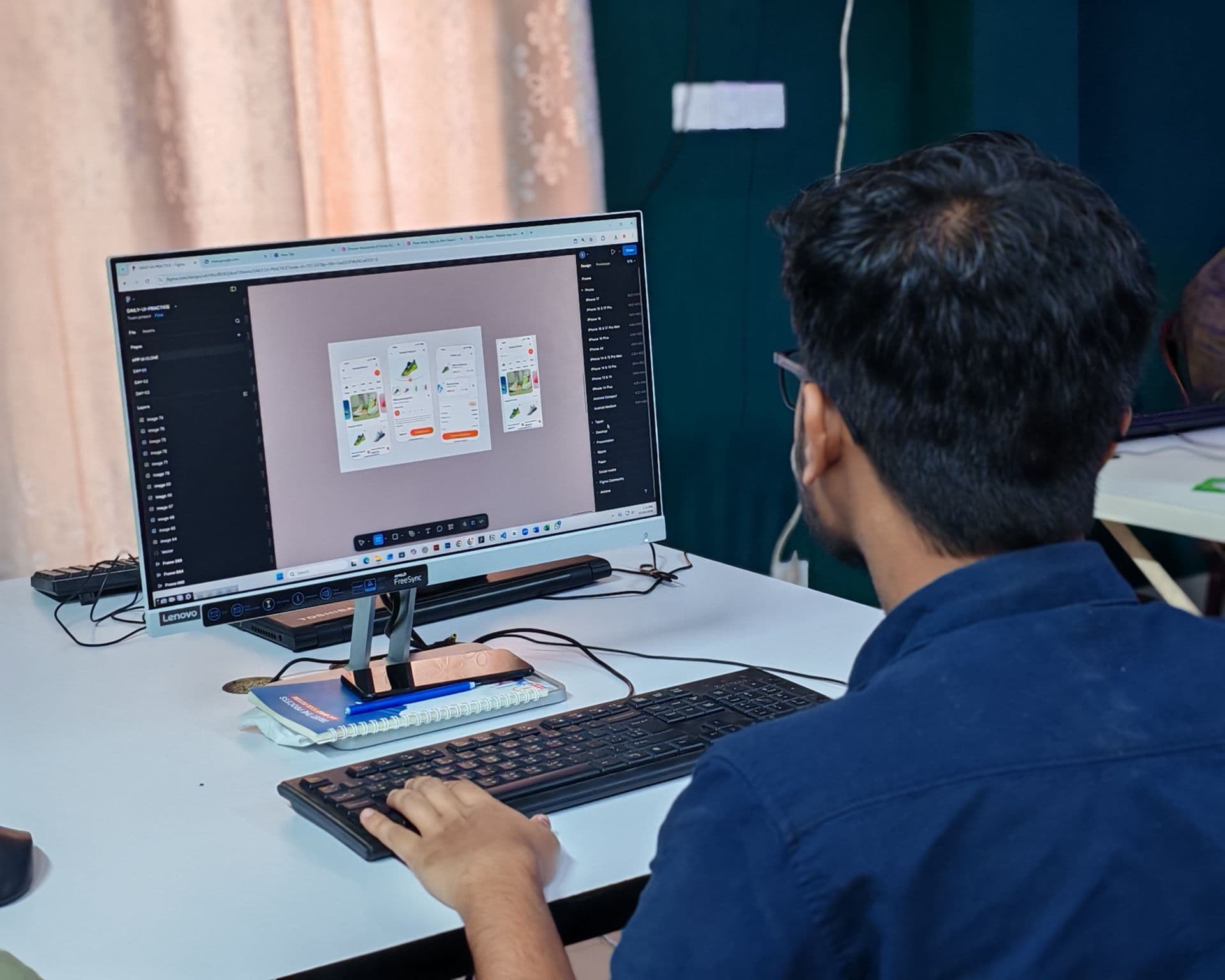 Young designer working on a web UI layout on a desktop monitor in an office