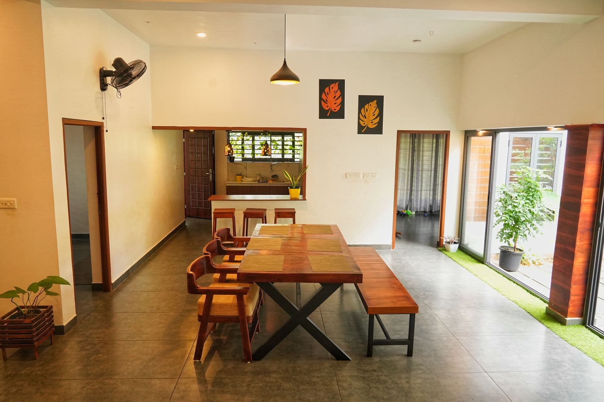 Open-plan dining area with a wooden table, bench, breakfast counter and glass doors to a courtyard