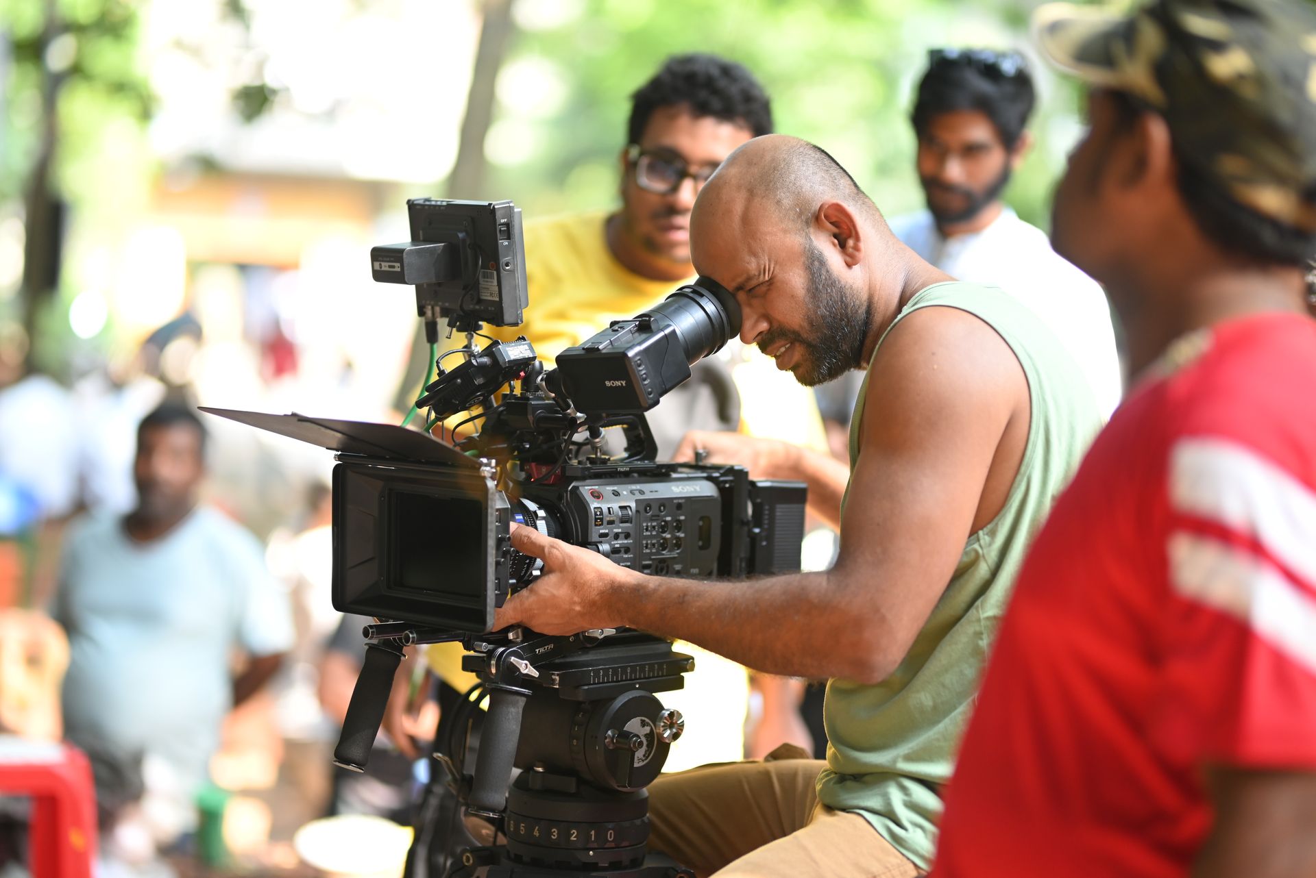 Cinematographer looking through the viewfinder of a cinema camera on an outdoor film set
