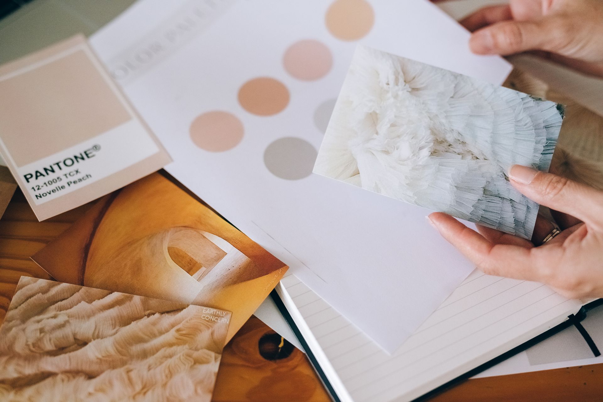 Hands holding a texture photo over peach colour swatches and moodboard cards