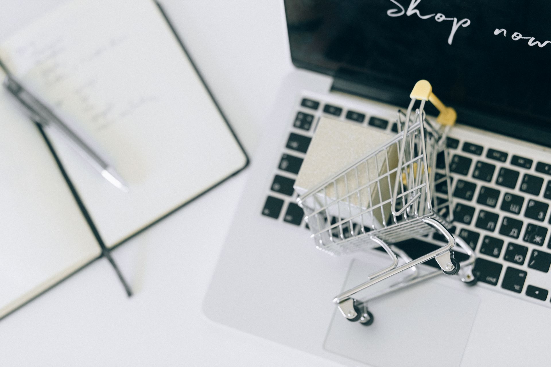 Miniature shopping cart on a laptop keyboard with Shop now on the screen