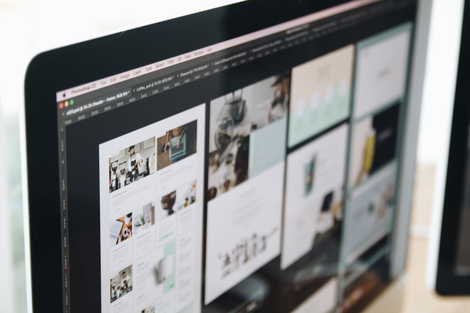 Monitor displaying website layout designs in an image editing program